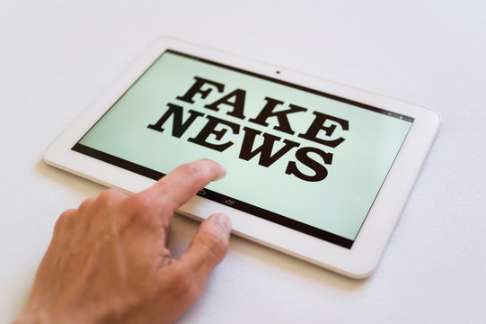 Fake News - user of digital device reads false information hoax, disinformation, propaganda. Misleading and brainwashing of reader