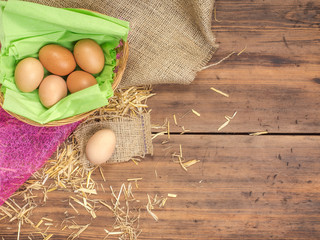 Rural eco background with brown chicken eggs, a piece of burlap and straw on the background of old wooden planks. The view from the top. Creative background for Easter cards or menu