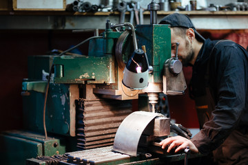 Portrait of man in workers uniform using drilling unit to make metal parts