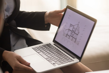 Close up of laptop in female hands with architectural plan of two story house on the screen. Realtor or building company agent showing house section cut drawing, offering property for sale