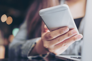A business woman holding and using smart phone and laptop in office