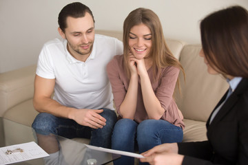 Happy couple talking over terms and conditions of home purchase agreement to real estate broker, future property owners discussing mortgage interest with advisor, making deal to rent apartment