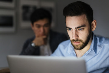 Serious banker looking at online data in laptop