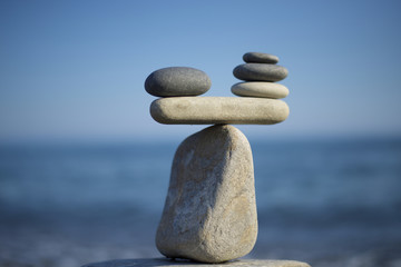 Stones pile background. Scales balance. Balanced stones on the top of boulder. Decide problem. To weight pros and cons. Balance of stones on a blue sky background with a copy space.
