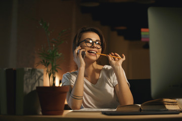 Young smiling woman designer talking by mobile phone