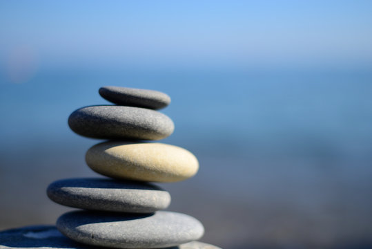 Zen spa stones with blue water and sky. Balanced stones background with copy space. Spa symbol. Beautiful picture. Symbol of stability. Stones pile background.