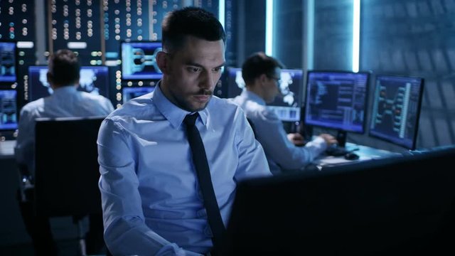 Close-up of Operations Engineer Working on His Computer With Multiple Displays in Monitoring Room. Shot on RED EPIC-W 8K Helium Cinema Camera.