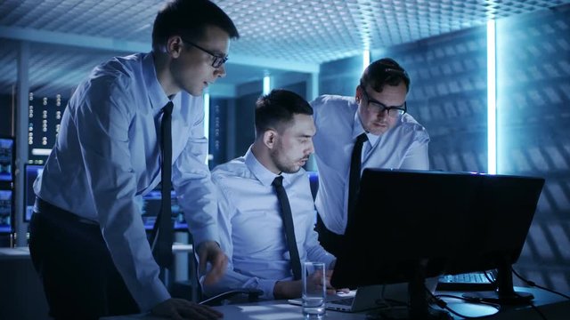 Three Operations Engineers Solving Problem in a Monitoring Room. In System Control Room Multitple Displays Show Various Data.   Shot on RED EPIC-W 8K Helium Cinema Camera.