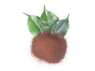 Pile of ground coffee with green leaves from top view