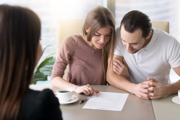 Smiling family couple reading contractual terms before signing contract, examining documents to make decision about mortgage, considering investment in property, calculating total loan liabilities