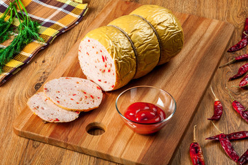 Delicious homemade sausage with hot pepper on a wooden cutting board closeup