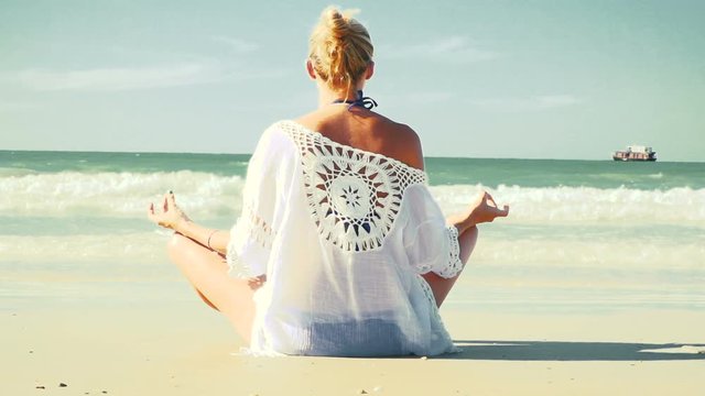 junge, blonde Frau macht Yoga am Strand