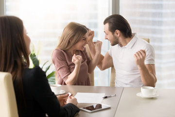 Funny couple excited by purchasing real estate meeting with agent to get the keys, delighted young family enjoys buying first apartment, achieving goal, affordable property, home loan with low rates