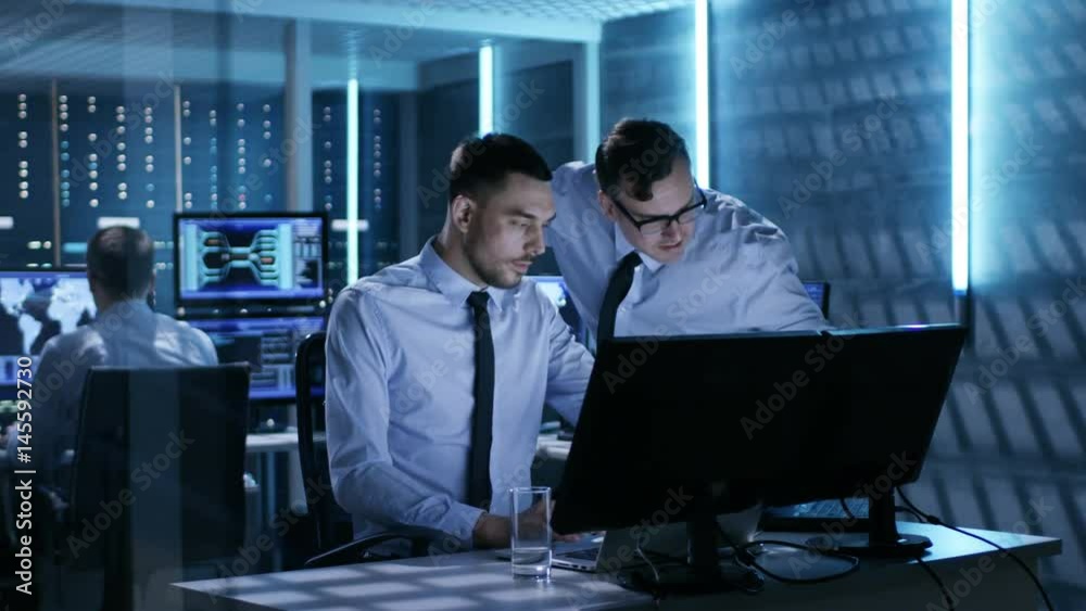 Aufkleber two operation engineers working on solving problems in system control room. in the background their 
