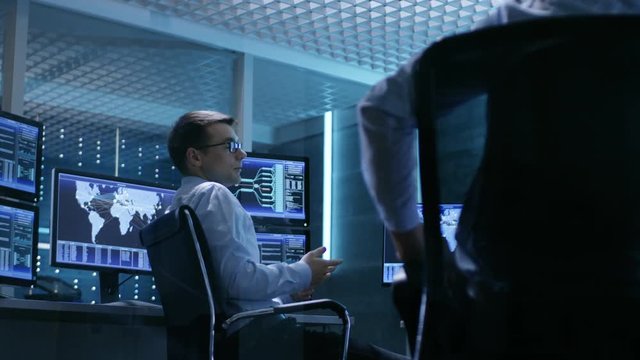 Team of Technical Moderators Have Discussion in Monitoring Room. System Control Room is full of Working Displays.  Shot on RED EPIC-W 8K Helium Cinema Camera.
