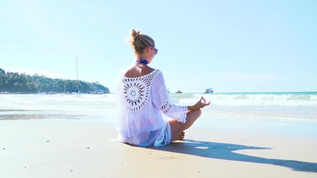 junge, blonde Frau macht Yoga am Strand