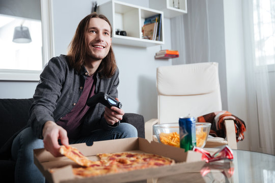 Smiling man gamer sitting at home indoors and play games