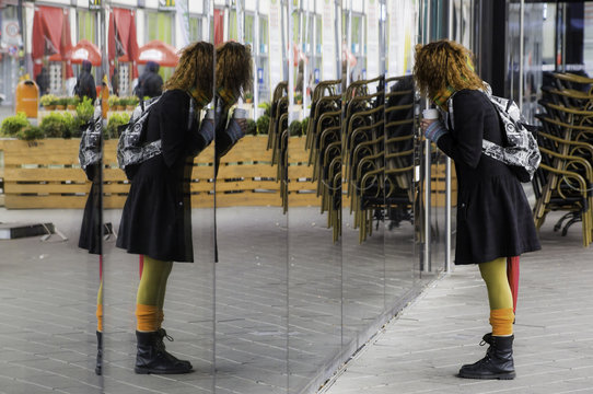 eine Frau will einkaufen, steht vor einem Schaufenster und spiegelt sich im Glas