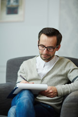 Serious psychologist making notes while listening to patient story