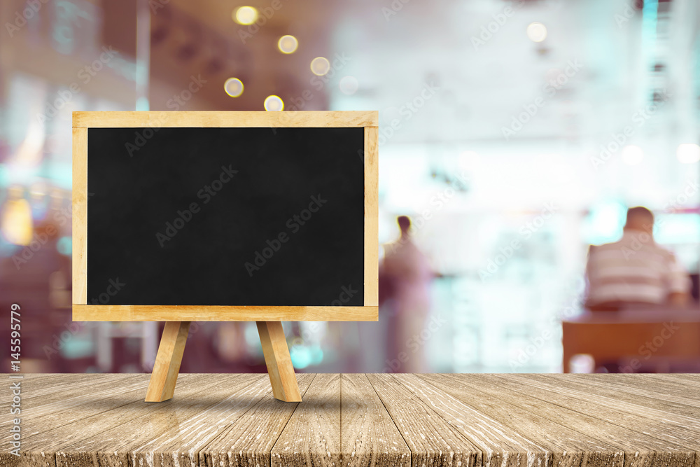 Poster Blackboard menu with easel on wooden table with blur restaurant background, Copy space for adding your content