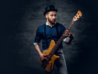 Studio portrait of the hipster bass player dressed in cylinder hat.