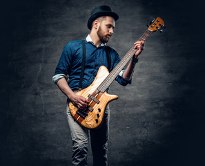 Studio portrait of the hipster bass player dressed in cylinder hat.