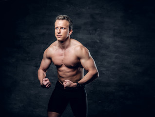 Fototapeta premium Portrait of shirtless athletic male with crossed arms over dark grey background.