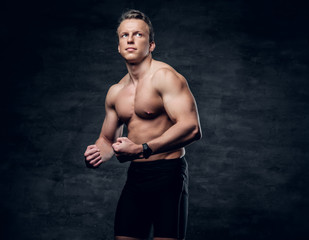 Obraz na płótnie Canvas Portrait of shirtless athletic male with crossed arms over dark grey background.