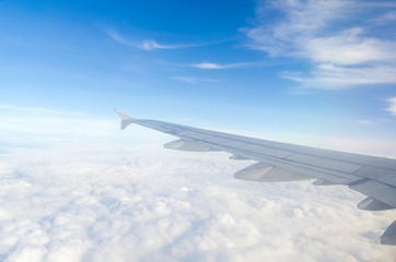 Wing of airplane flying above the cloud