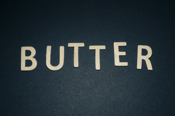 Butter written with colorful wooden letters on a blue background