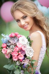 Naklejka premium Beautiful young girl with a bright bridal bouquet on a nature background in summer