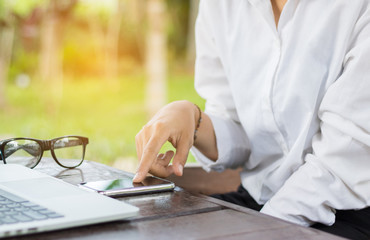 Close up woman hand use cell phone with laptop in coffee shop.