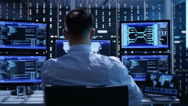 Technical Controller Working at His Workstation with Multiple Displays. Displays Show Various Technical Information. He's Alone in System Control Center.Shot on RED EPIC-W 8K Helium Cinema Camera.