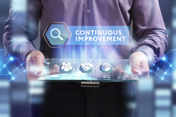 Business, Technology, Internet and network concept. Young businessman working on a virtual screen of the future and sees the inscription: Continuous improvement