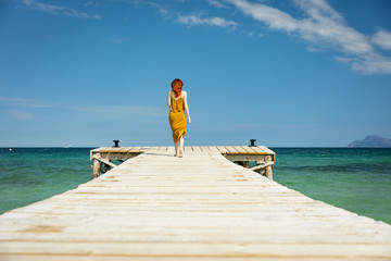 red haired woman at ocean pier in sunny weather