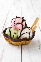 Ice cream scoops served in waffle basket on white wooden table

