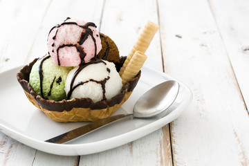 Ice cream scoops served in waffle basket on white wooden table

