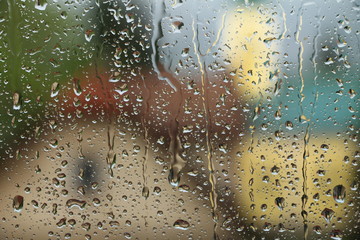 Rain drops on window with house and church in background 