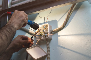 Electrician welding electrical wire. Installation of electricity - obrazy, fototapety, plakaty