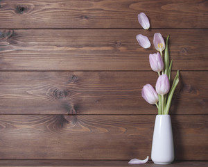 Wooden background witn pink tulips on vese.