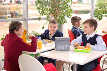 Children sitting at cafeteria table while eating lunch