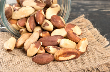 Brazil nuts are scattered from the jar on burlap closeup