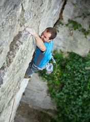 Naklejka na ściany i meble male rock climber. rock climber climbs on a rocky wall. man makes hard move