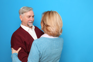 Happy senior couple dancing on color background