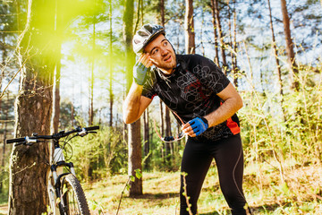 Naklejka premium People, active healthy lifestyle and extreme. Rear shot of Caucasian professional rider in helmet, cycling clothes recreation after hard workout with bike in the forest or mountains.