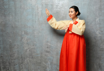 Beautiful young woman dressed in traditional clothing on grey background