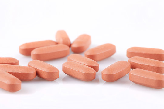 Ibuprofene pills on a white surface. Brown pills isolated on white background.