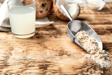 Metal scoop with coconut flour on wooden background