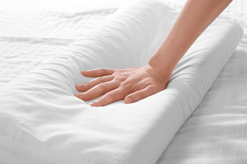 Female hand touching white orthopedic pillow. Healthy posture concept.