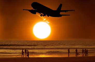 Fototapeta na wymiar Aircraft take off and the sunset and people on the beach
